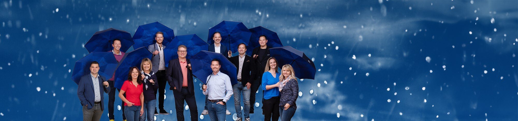 das Team der UNIQA Generalagentur Hauser und Partner mit dunkelblauen Regenschirmen.